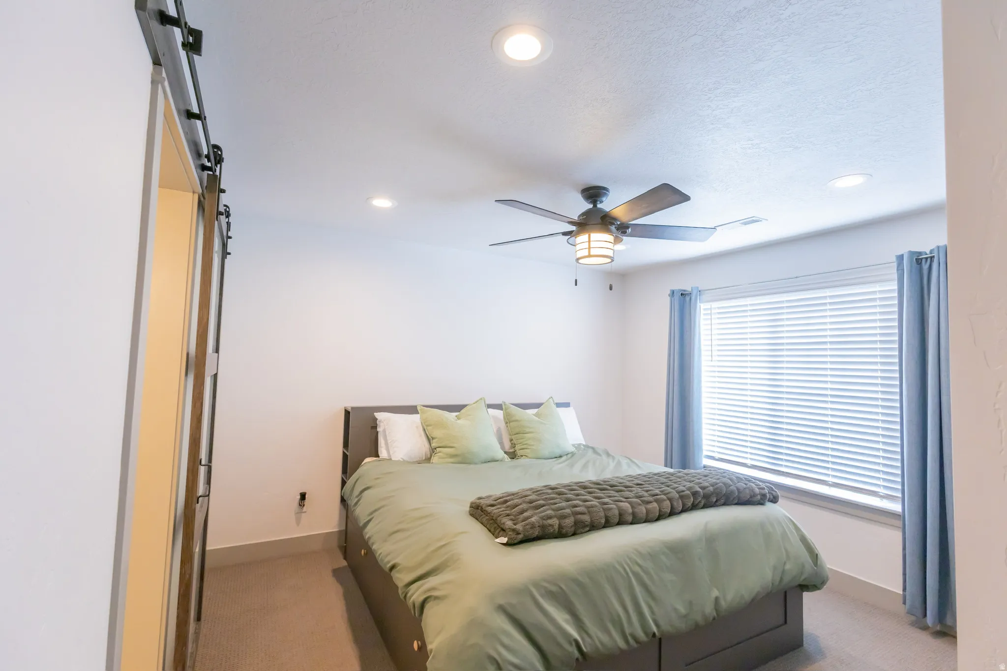 Bedroom with a barn door, light colored carpet, recessed lighting, and ceiling fan