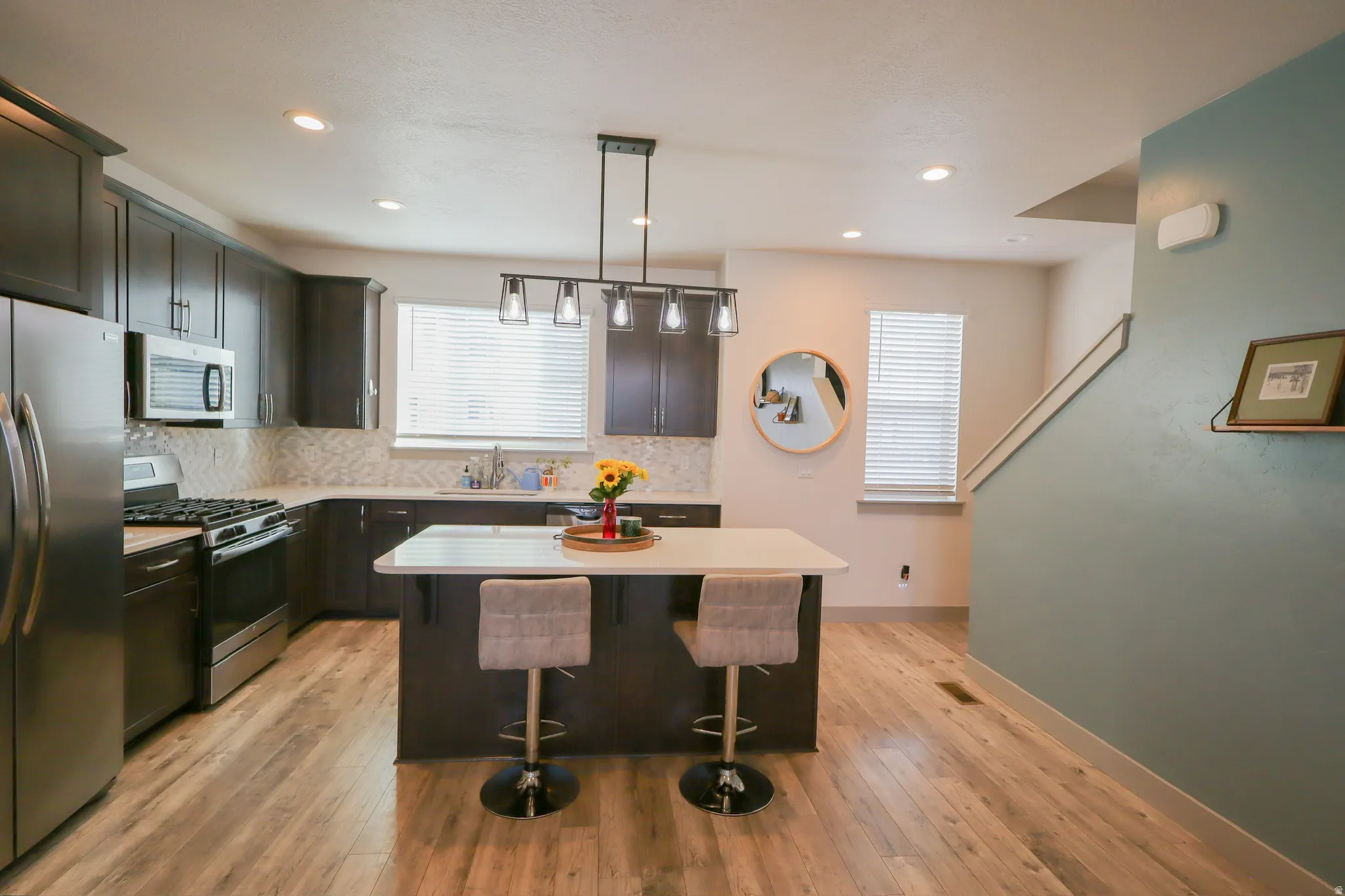 Kitchen with stainless steel appliances, a kitchen breakfast bar, decorative backsplash, and light wood-type flooring