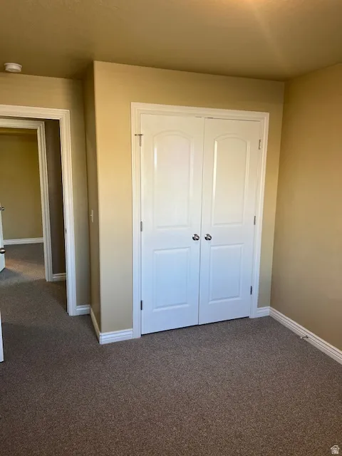 Unfurnished bedroom with dark carpet and a closet