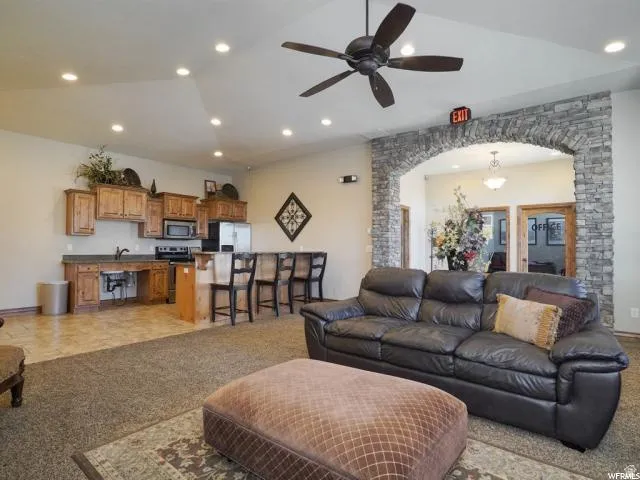 Living area featuring arched walkways, a ceiling fan, light colored carpet, lofted ceiling, and recessed lighting