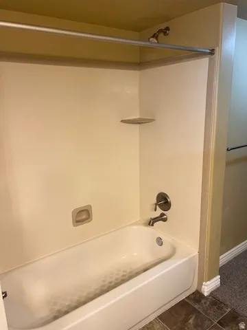 Bathroom featuring bathing tub / shower combination and dark tile patterned flooring