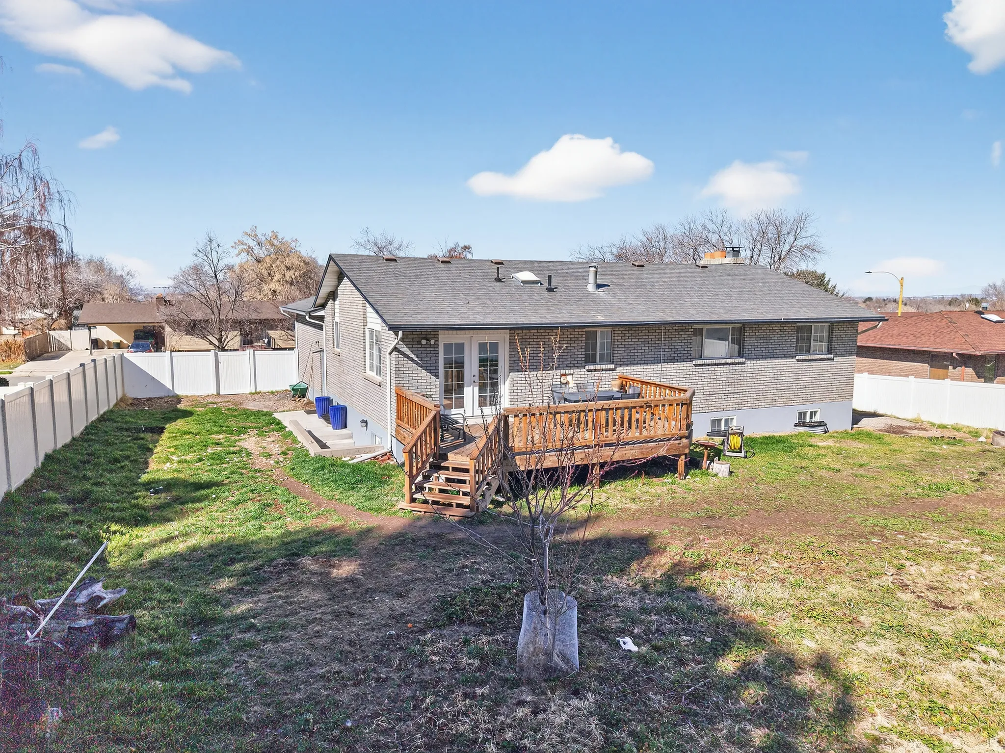 Rear view of property featuring a fenced backyard, brick siding, a wooden deck, a chimney, and french doors