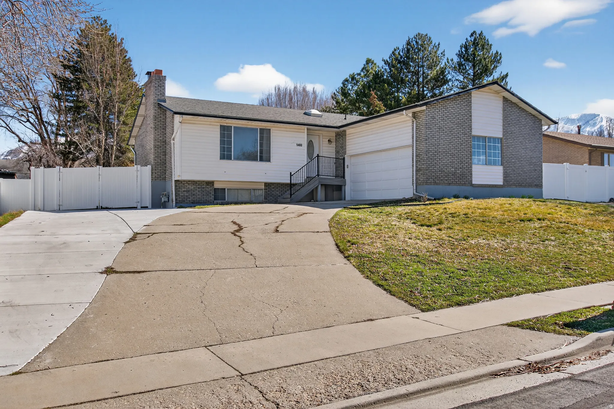 View of front of house featuring concrete driveway, brick siding, a gate, a chimney, and a mountain view