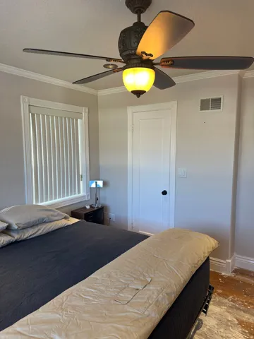 Bedroom with crown molding, ceiling fan, and a textured ceiling