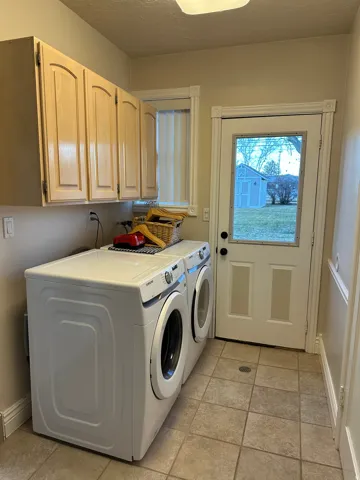 Laundry area featuring washing machine and dryer, a textured ceiling, and cabinet space