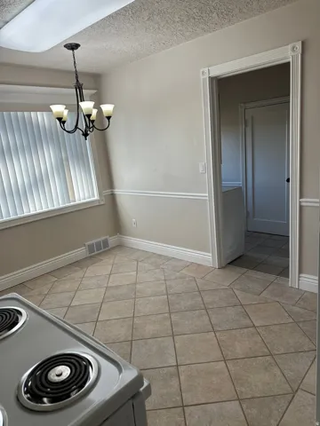 Unfurnished dining area featuring a textured ceiling and a chandelier