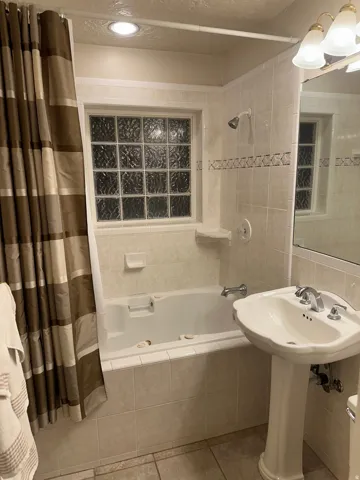 Bathroom with tiled shower / bath, tile walls, and light tile patterned floors