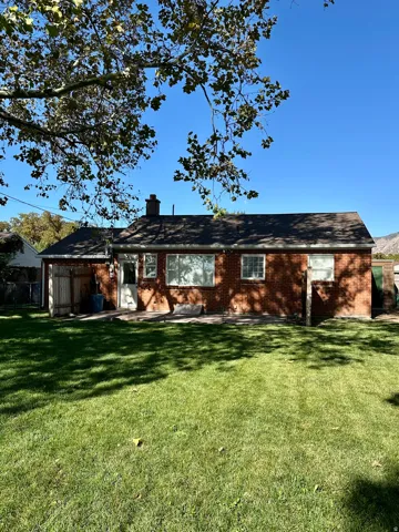 Back of house with brick siding, a chimney, and a patio area