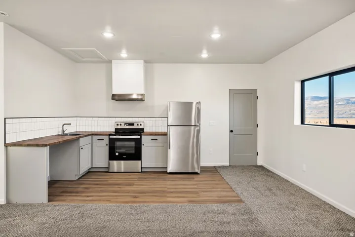 Kitchen with wooden counters, stainless steel appliances, recessed lighting, dark carpet, and dark wood-style flooring