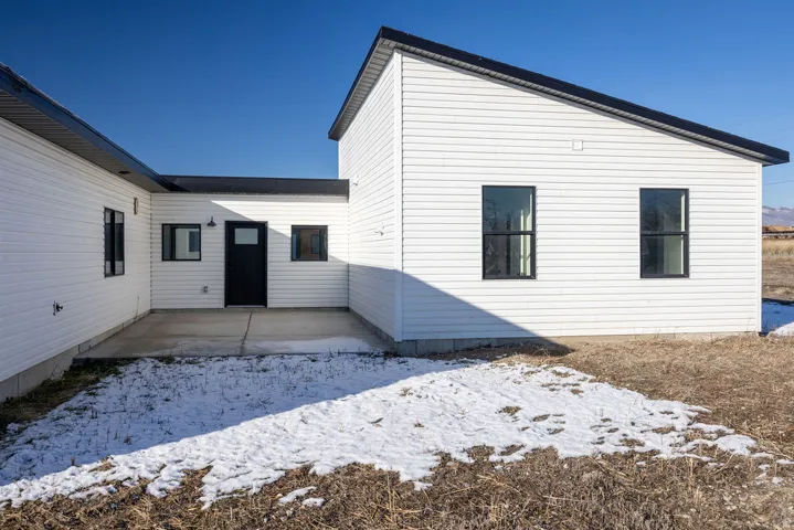 Snow covered back of property with a patio