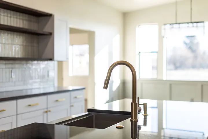 Kitchen featuring white cabinetry, open shelves, decorative backsplash, and dark countertops