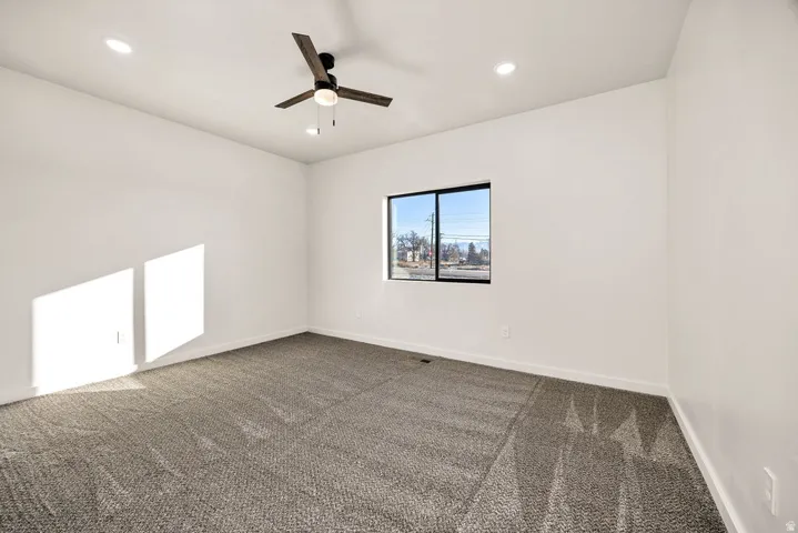 Empty room featuring dark carpet, a ceiling fan, and recessed lighting