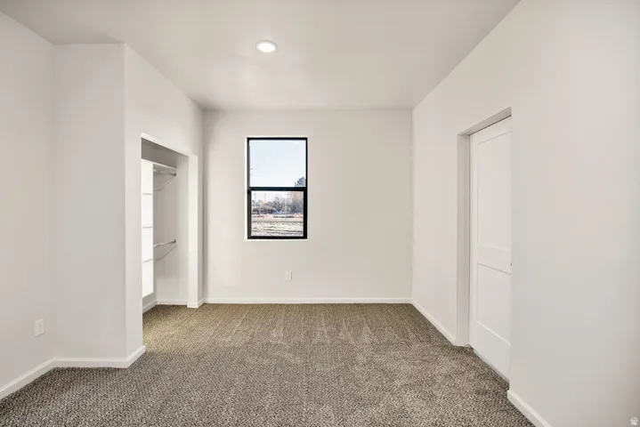 Unfurnished bedroom with dark colored carpet and baseboards