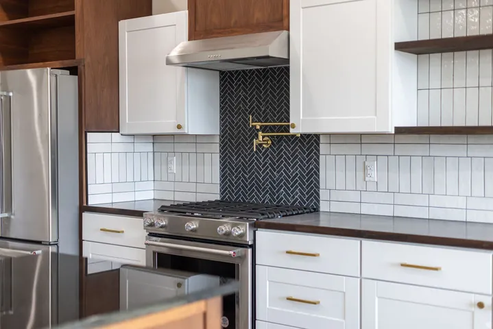 Kitchen with open shelves, white cabinets, stainless steel appliances, and exhaust hood