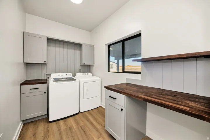 Laundry area with cabinet space, light wood finished floors, and independent washer and dryer