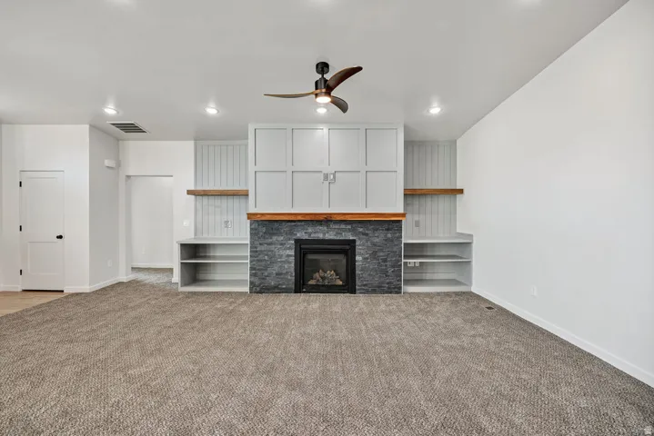 Unfurnished living room with a ceiling fan, a glass covered fireplace, carpet flooring, and recessed lighting
