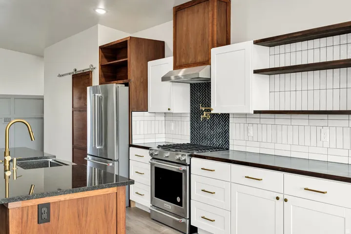 Kitchen with open shelves, stainless steel appliances, light wood finished floors, exhaust hood, and white cabinets