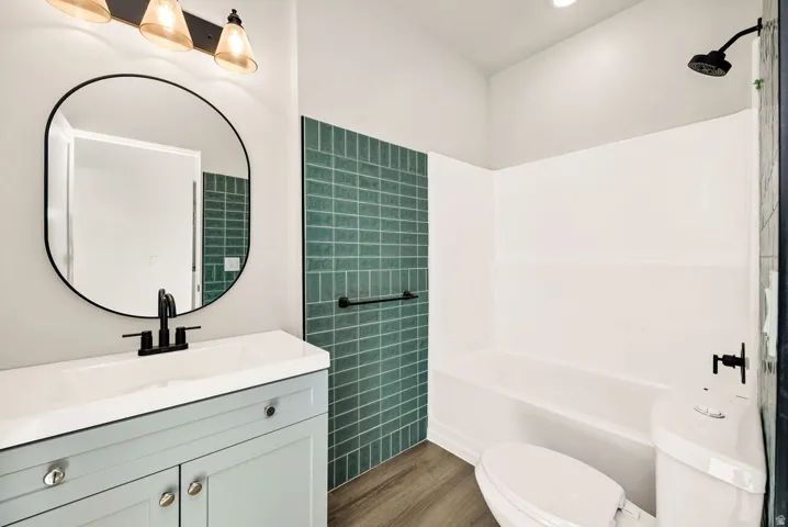 Full bathroom with vanity, dark wood-style floors, and shower / washtub combination