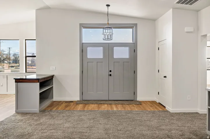 Entryway with lofted ceiling, light wood-style flooring, and light colored carpet