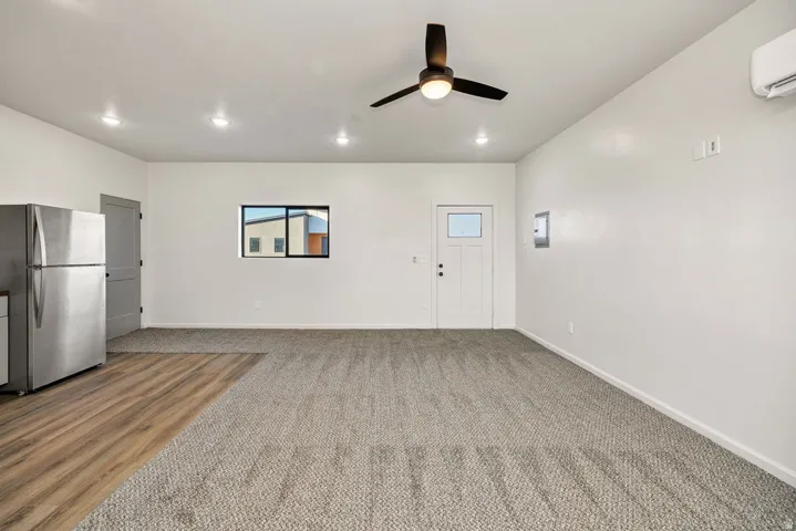 Unfurnished living room featuring a ceiling fan, recessed lighting, and light carpet