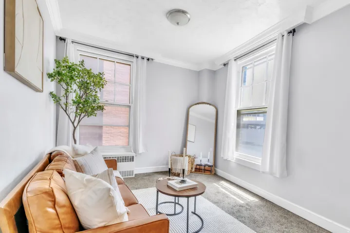 Living area featuring ornamental molding, carpet flooring, and radiator heating unit
