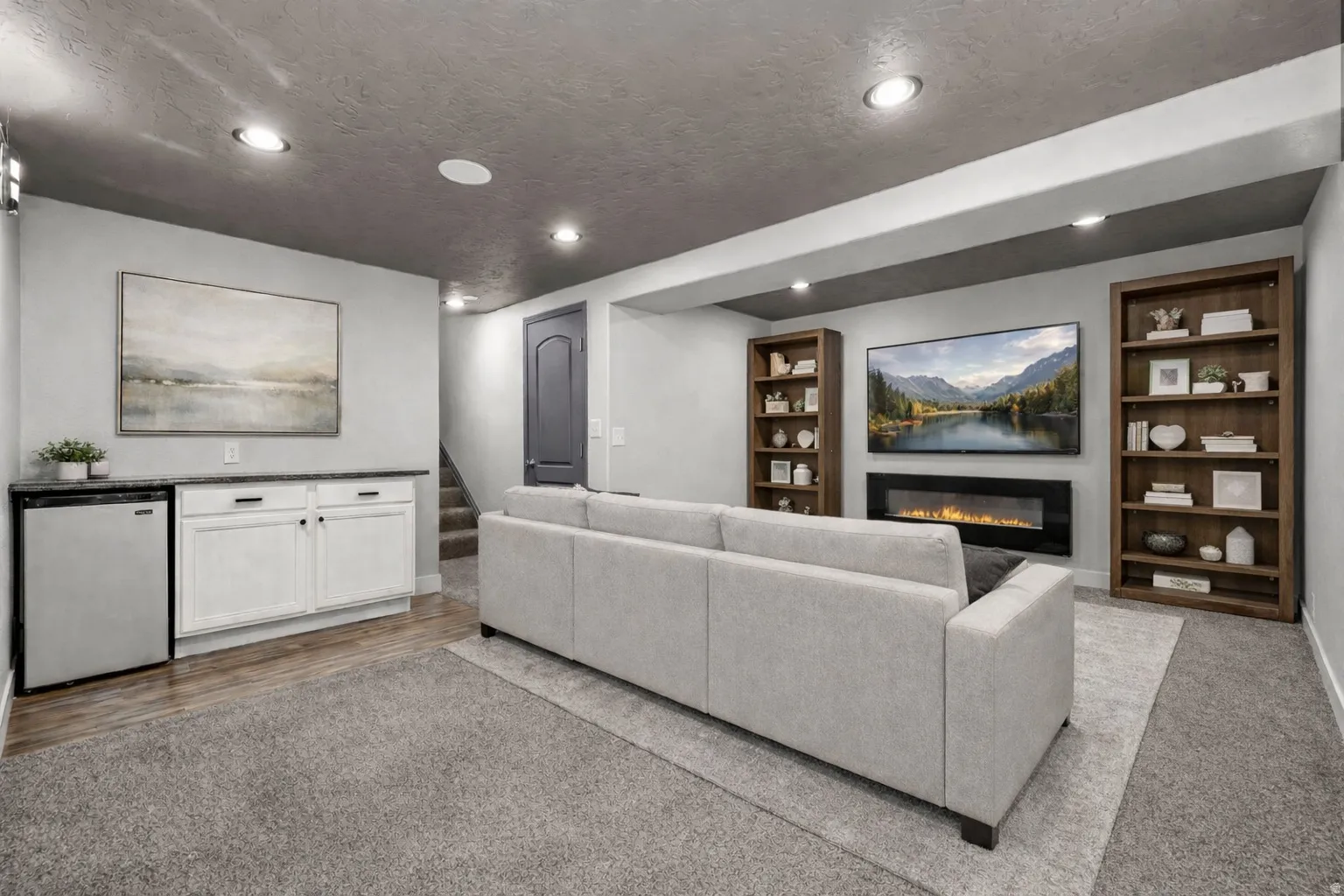 Living area featuring built in shelves, carpet floors, a glass covered fireplace, recessed lighting, and a textured ceiling