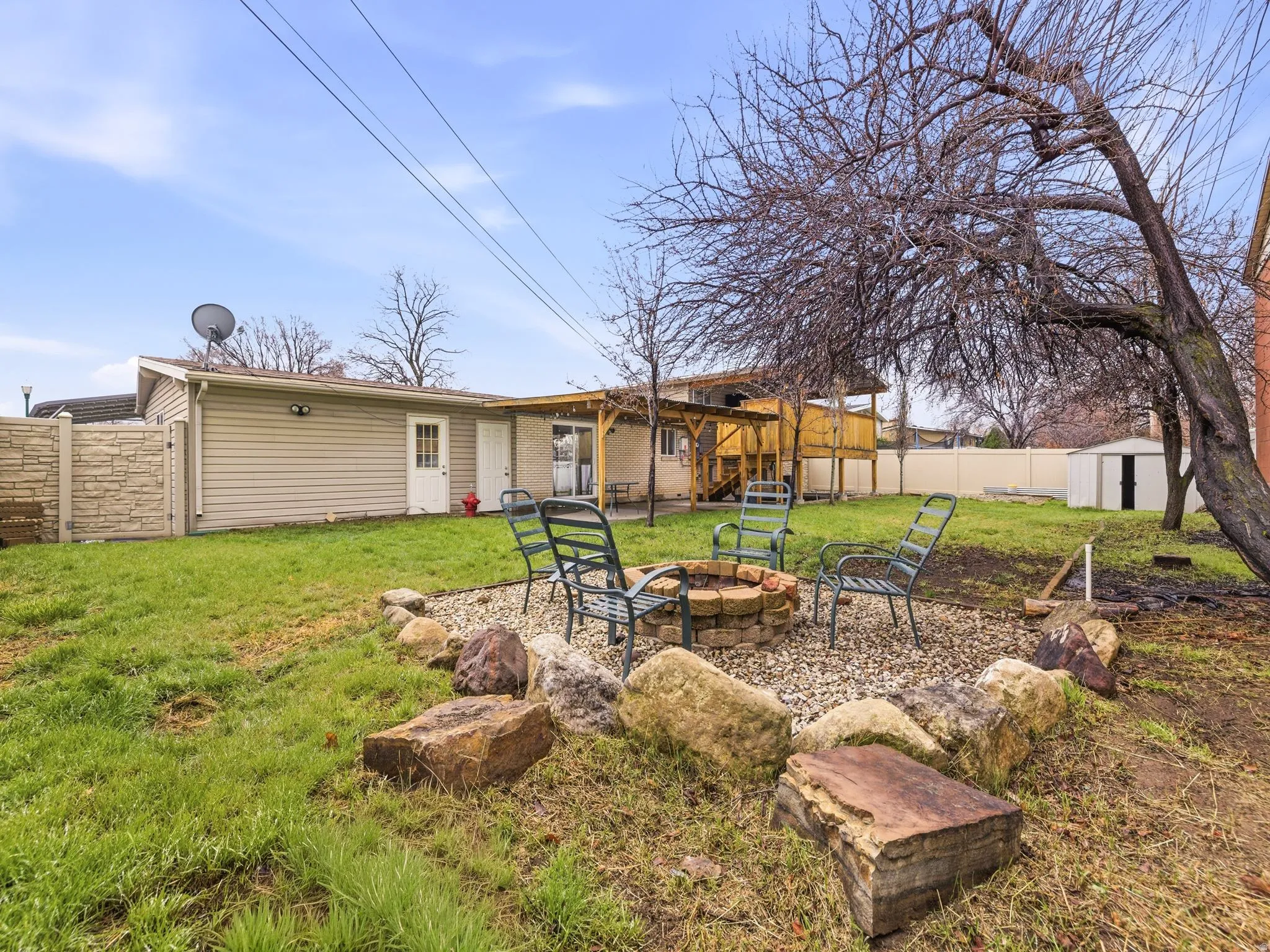 Fenced backyard with an outdoor fire pit, a storage shed, and a patio