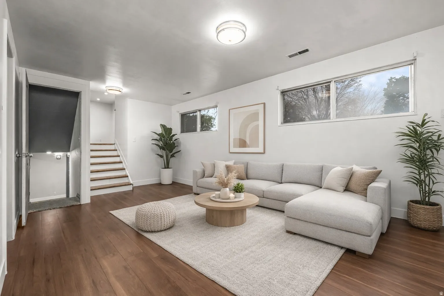 Living room featuring dark wood-style floors and stairs