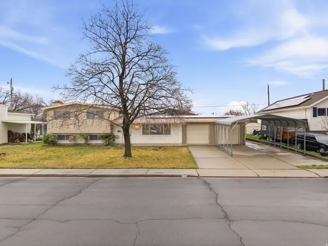 View of front of house with a front yard, driveway, a garage, and brick siding