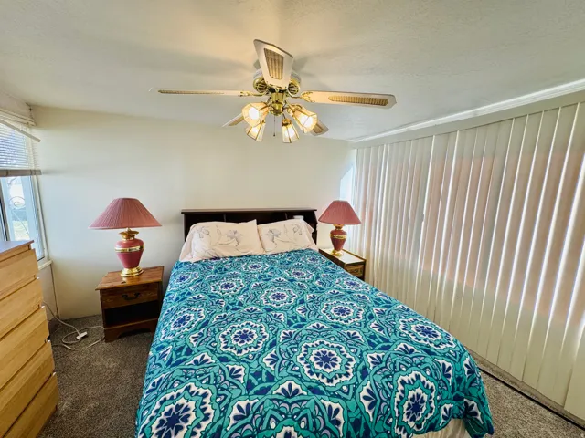 Bedroom featuring dark colored carpet, a textured ceiling, and ceiling fan