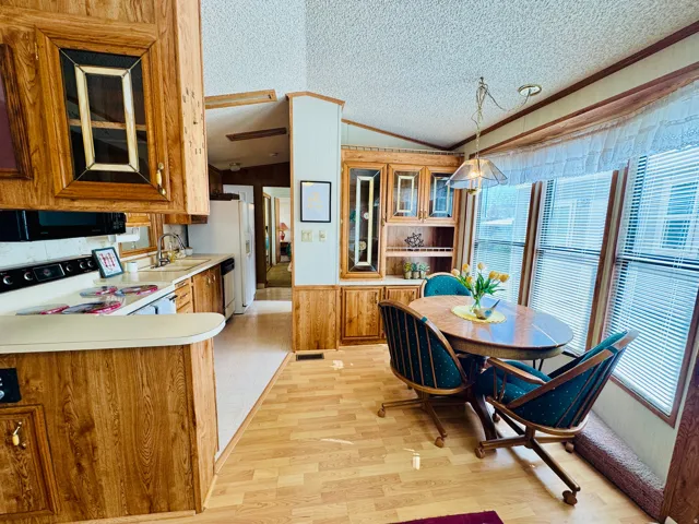 Kitchen with light countertops, white electric stove, wood finish cabinets, a peninsula, and black microwave