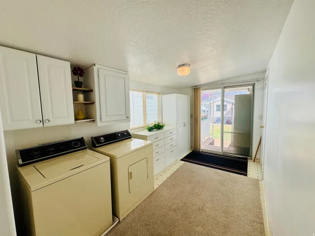 Laundry area with washer and dryer, cabinet space, and light carpet