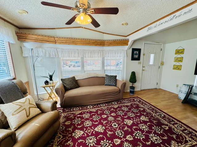 Living room featuring crown molding, ceiling fan, and light wood finished floors