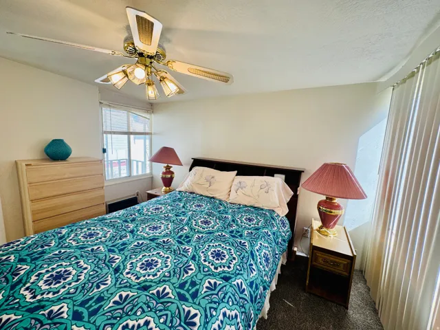 Bedroom featuring ceiling fan and dark carpet