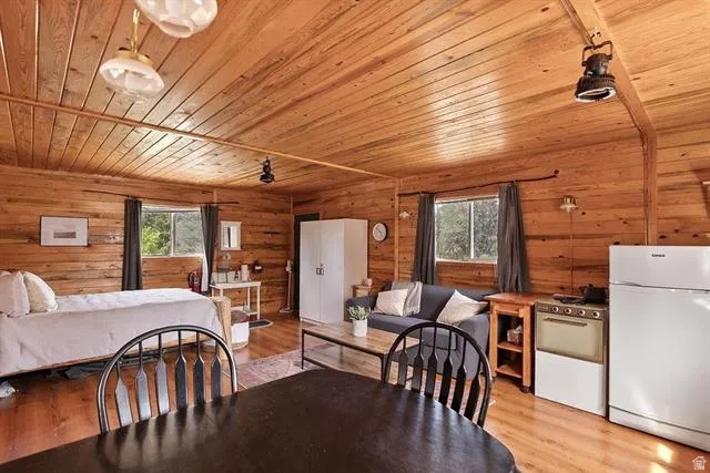 Dining area with wooden ceiling, light wood-type flooring, and wood walls