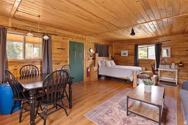 Bedroom with wood ceiling, light wood-style flooring, and wood walls