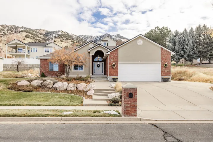 View of front of property featuring an attached garage, driveway, brick siding, and stucco siding