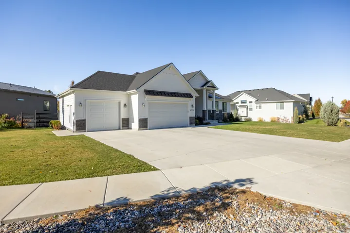 View of front of home with a garage, a front lawn, concrete driveway, stone siding, and a metal roof