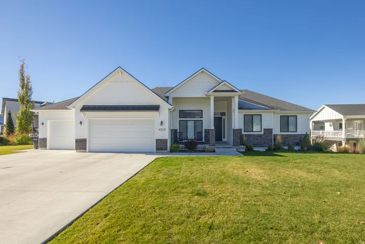 Craftsman inspired home featuring stone siding, an attached garage, driveway, and a front yard