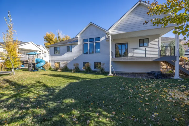 Back of house with a playground and a lawn