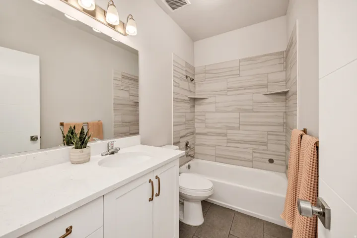 Bathroom featuring vanity, bathing tub / shower combination, and dark tile patterned floors
