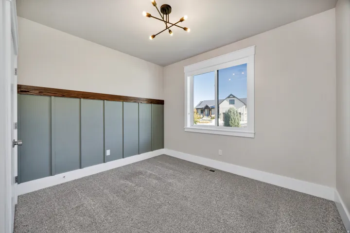 Carpeted spare room with a chandelier and baseboards