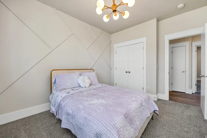 Carpeted bedroom featuring suspended lighting and baseboards