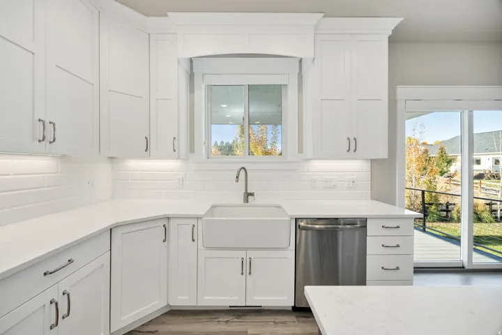 Kitchen featuring stainless steel dishwasher, white cabinetry, dark wood-type flooring, and plenty of natural light