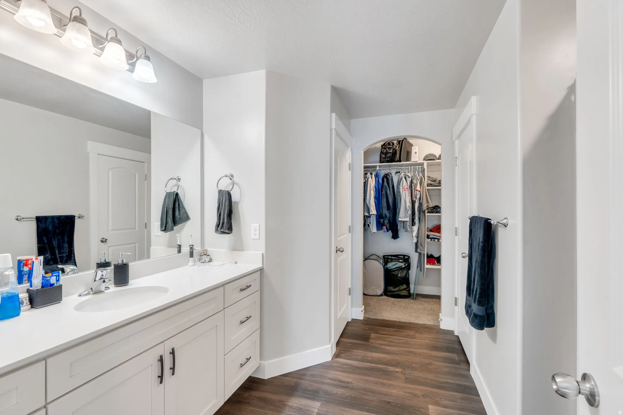 Full bathroom with vanity, dark wood finished floors, and a spacious closet