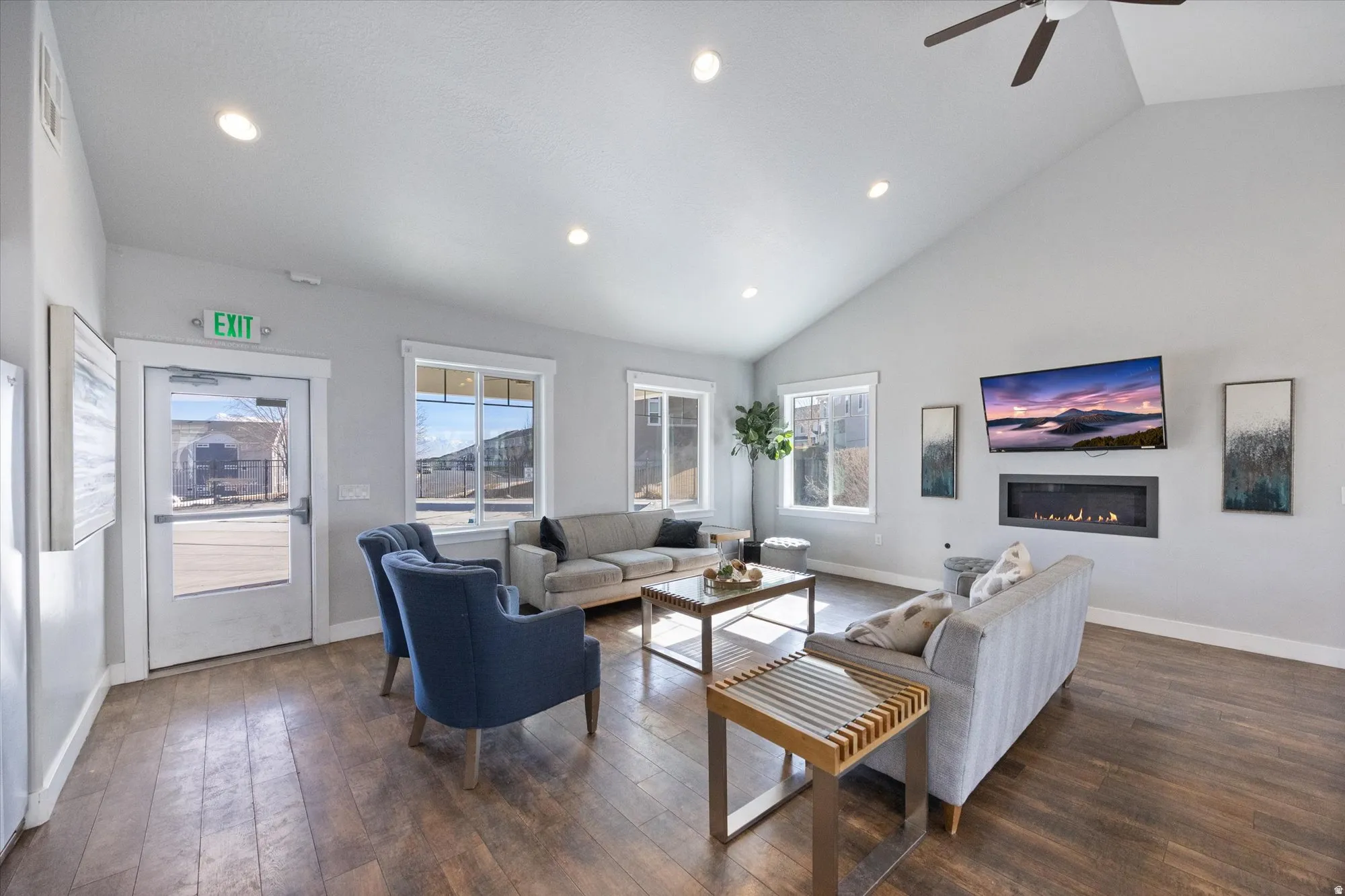 Living room featuring dark wood-style flooring, a glass covered fireplace, a ceiling fan, lofted ceiling, and recessed lighting