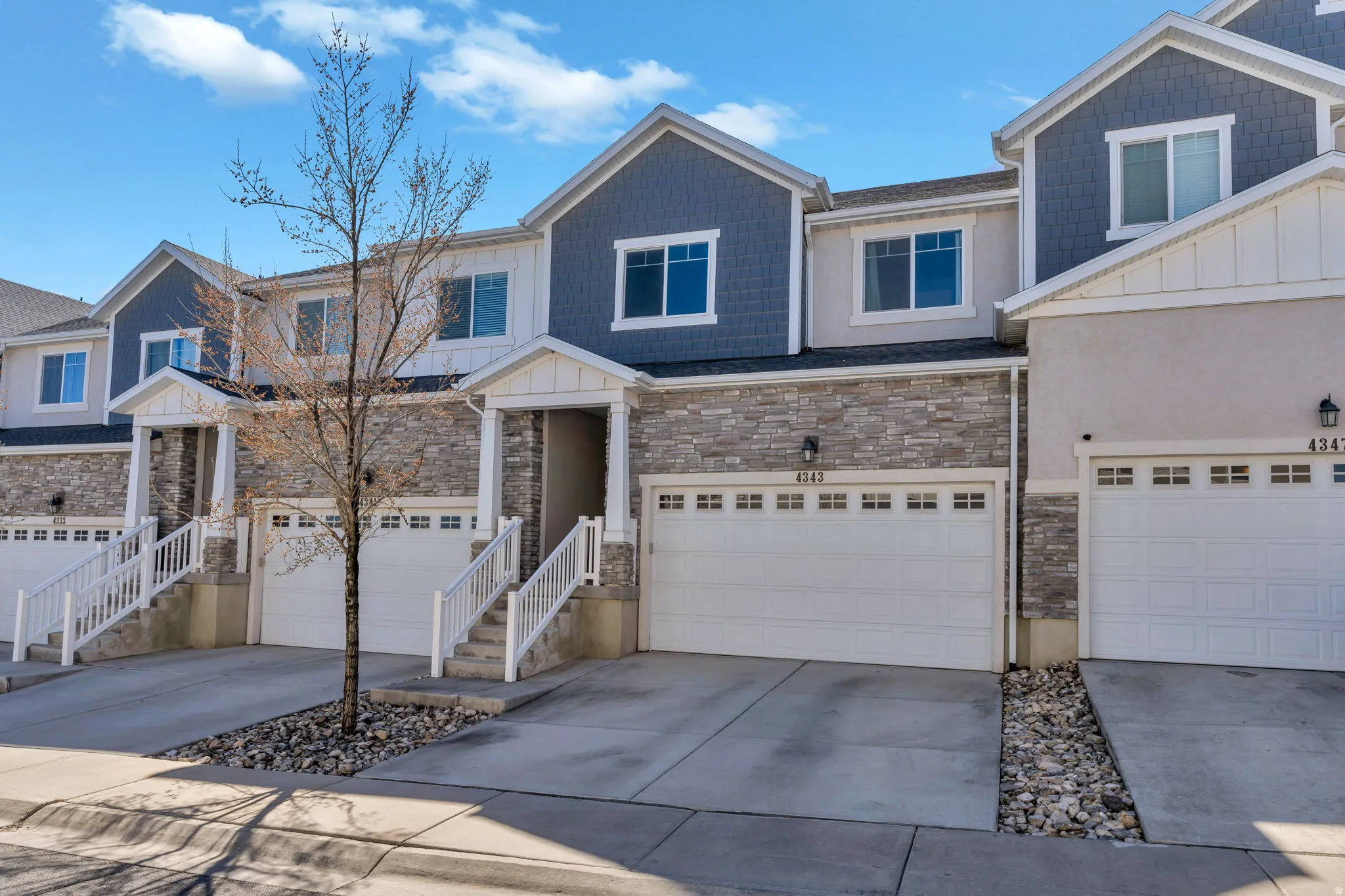 Craftsman house with board and batten siding, stone siding, and concrete driveway