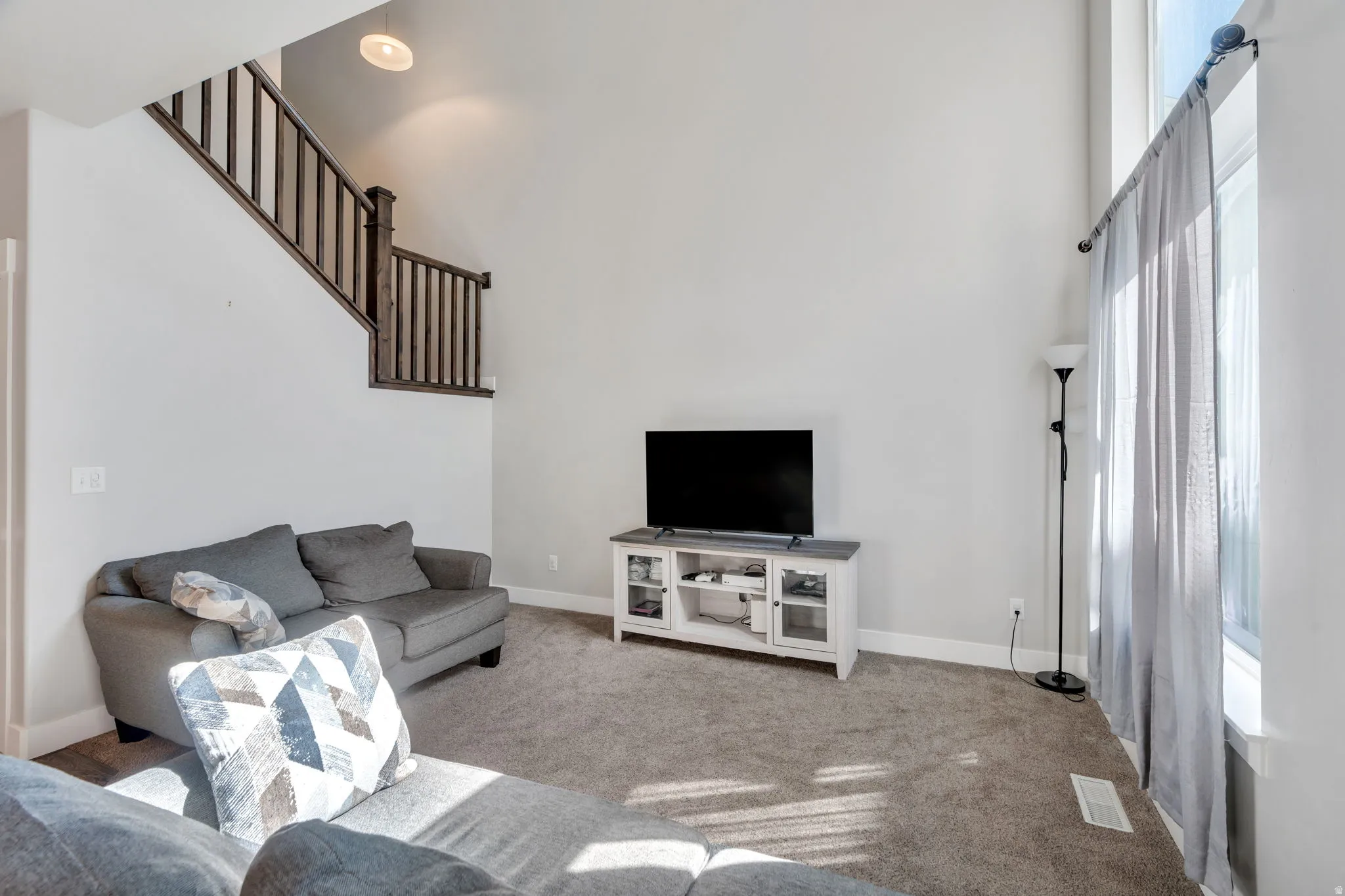 Living area with a high ceiling and carpet flooring