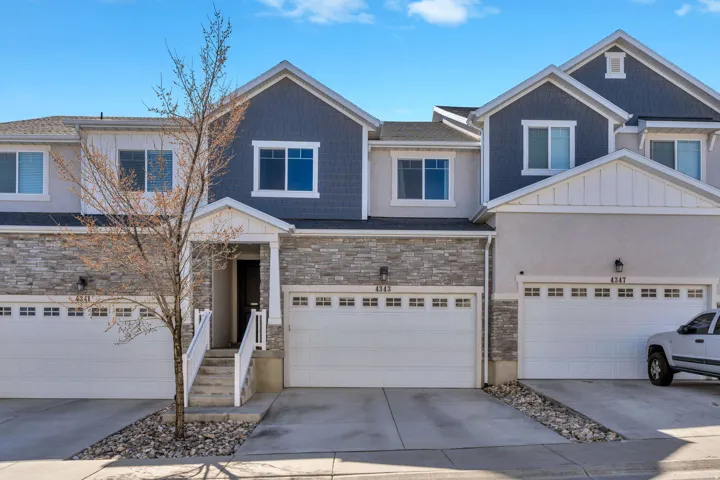 View of front of home with board and batten siding, driveway, stone siding, and an attached garage