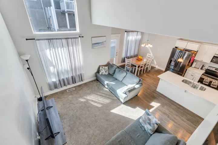 Living room featuring a high ceiling, suspended lighting, and dark wood-style floors
